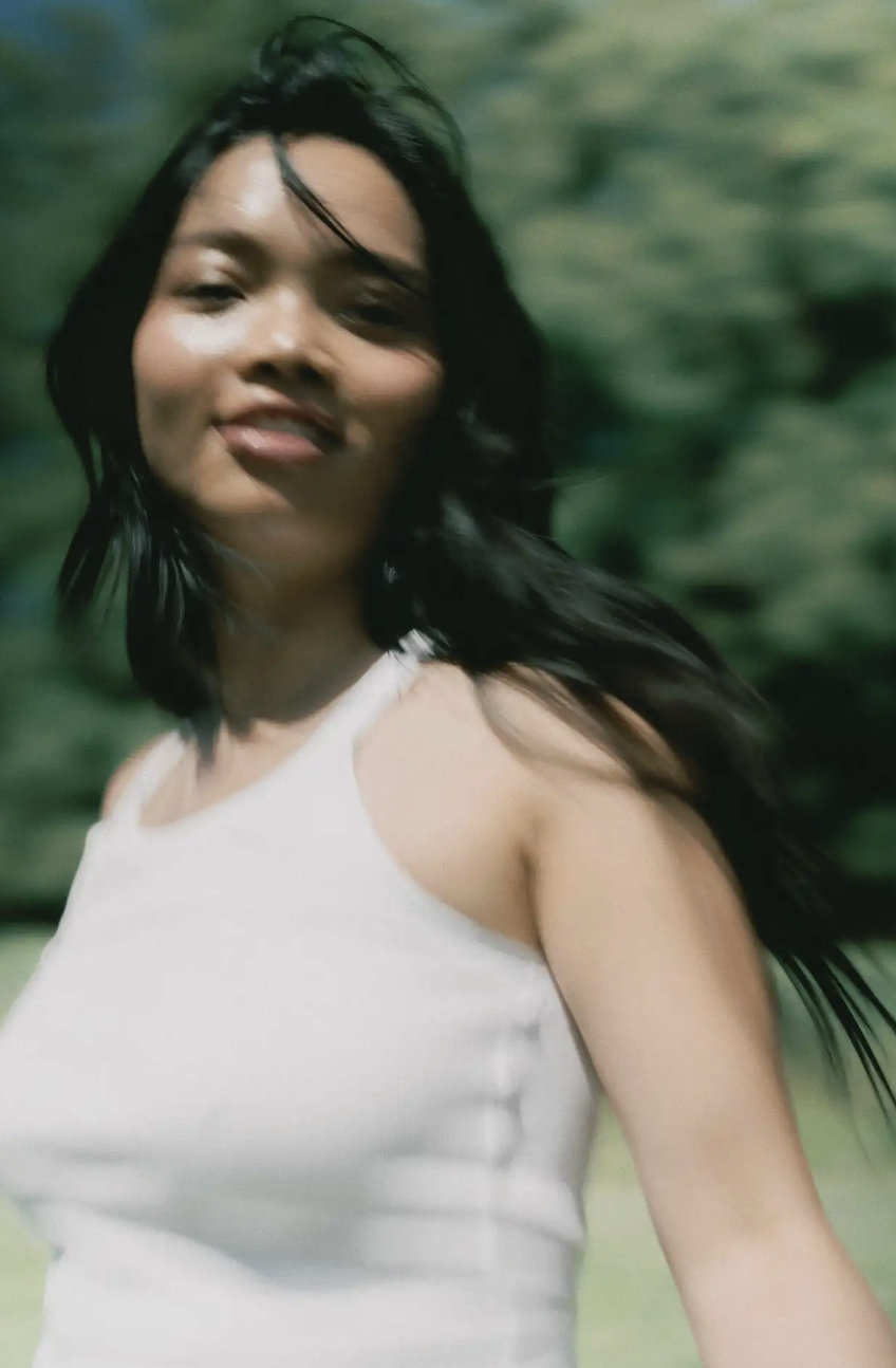 A woman moving through a sunlit green landscape
