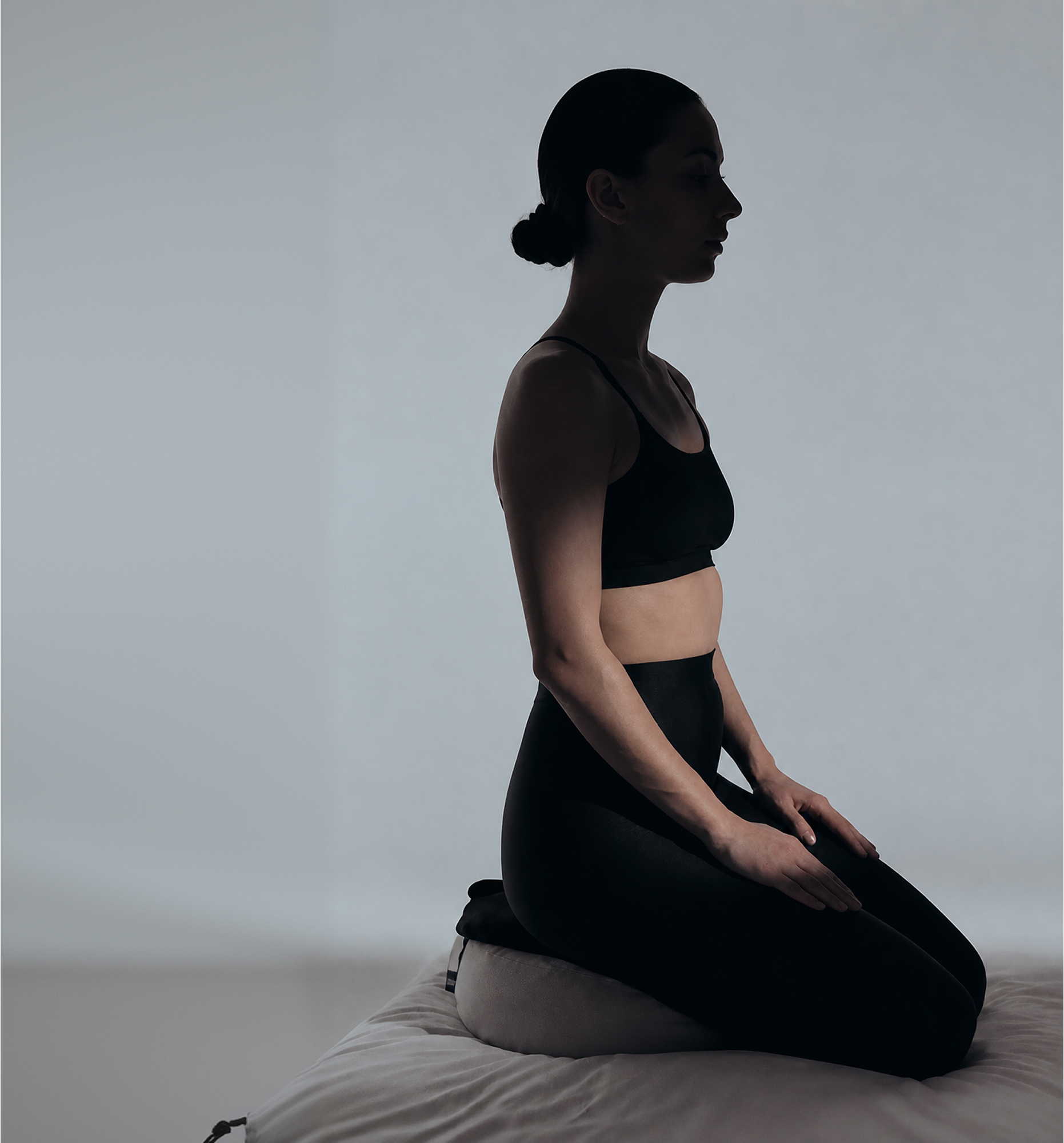 A woman sitting in profile against a soft studio backdrop